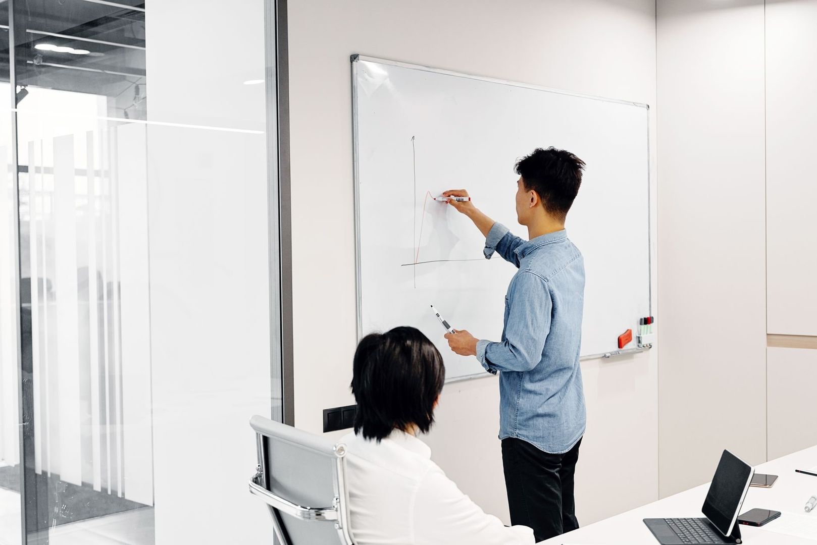 Person presenterar en kurva på whiteboard inför en kollega